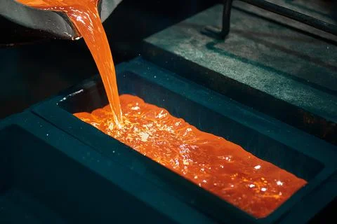 Pouring silver into graphite casting form in dark workshop Stock Photos