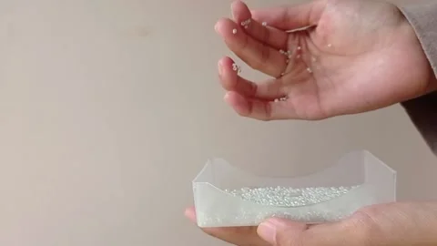 Pouring small pearls into a small box Stock Footage 146257338