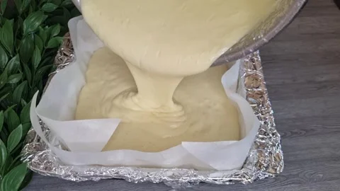 Pouring Smooth Cake Batter into Square Baking Pan Lined with Parchment Paper Stock Footage 344288220
