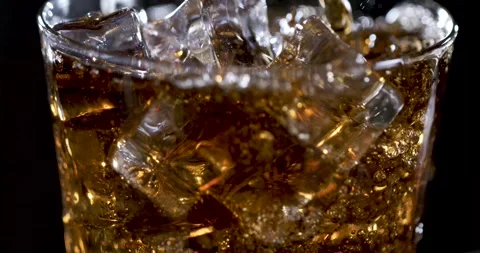 Pouring soda over ice in slow motion with bubbles rising and splashing Stock Footage 337845708