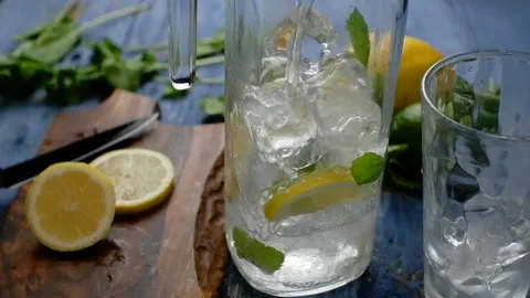 Pouring soda water from a decanter with ice lemon and mint. Making lemonade. Stock Footage