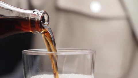 Pouring soft drinks from a bottle into a glass at a table Stock Footage 329458646