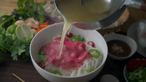 Pouring soup into authentic vietnamese pho rice noodle with raw beef Stock-Footage 196261256