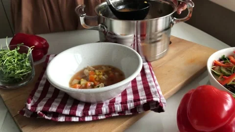 Pouring soup from a pot into a plate using a ladle Stock Footage 142589943