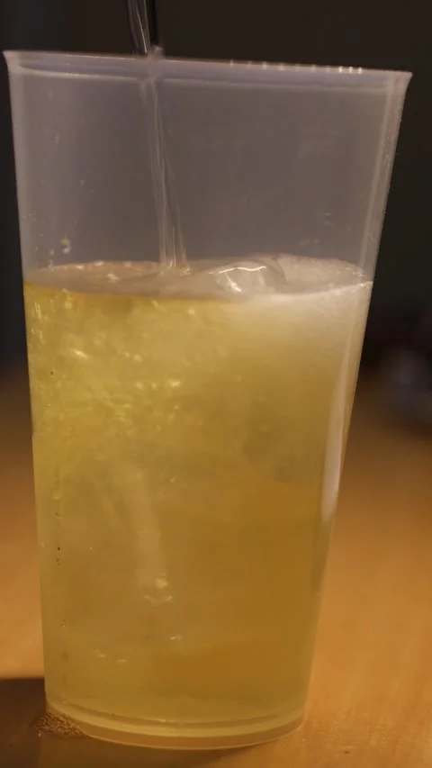 Pouring sparkling lemonade with ice in plastic cup Stock Footage 344815709
