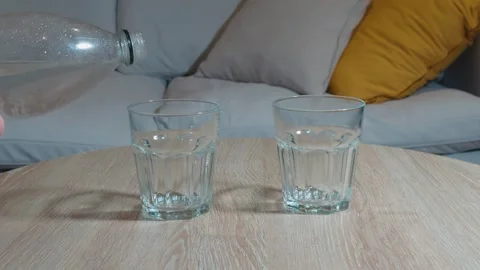 Pouring Sparkling Water into Two Glasses on a Wooden Table at Home Stock Footage 315197053