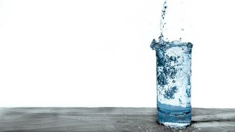 Pouring Stream Of Clear Blue Drinking Water Into An Overflowing Glass Cup Stock Photos