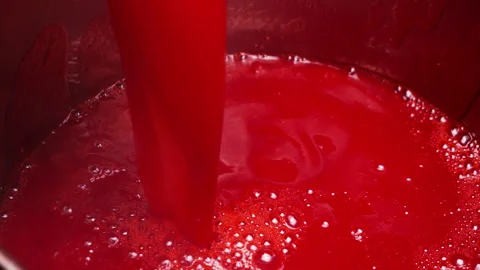 Pouring a stream of hot red currant juice into a cooking pan. Video stock 337675391