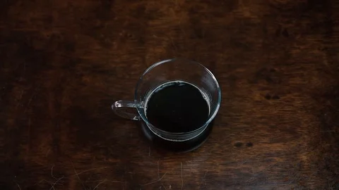 Pouring stream milk into a cup of coffee on wooden background 動画素材 108305499