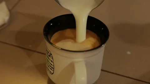 Pouring stream milk into a cup of coffi Stock Footage 84077830