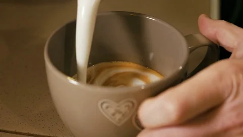Pouring stream milk into a cup of coffi Video stock 84077878