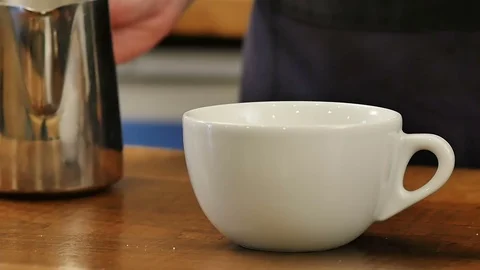 Pouring stream milk into a cup of espresso to make latte Stock Footage 75447904