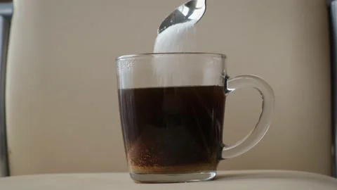 Pouring sugar into coffee or tea with a spoon, close-up Vidéo 221762360