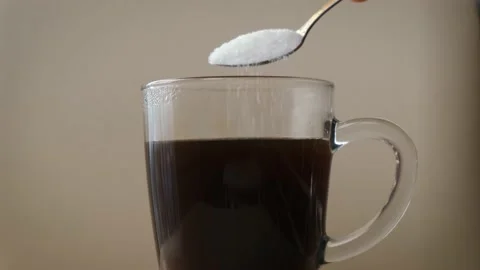Pouring sugar into coffee or tea with a spoon, close-up Vidéo 221763384