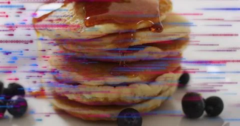 Pouring syrup over pancake stack sitting on kitchen countertop, with blueberries Stock Photos