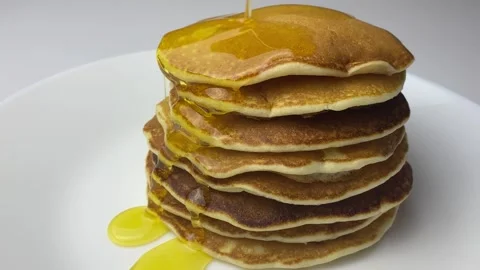 Pouring syrup over stack of fluffy buttermilk pancakes. Closeup view, slow Stock Footage 240914480