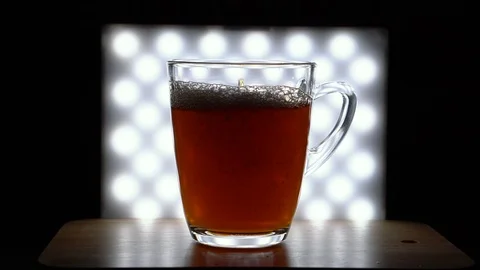 Pouring Tea in Backlit Glass Cup - 4K Real Time Stock Footage 105839059