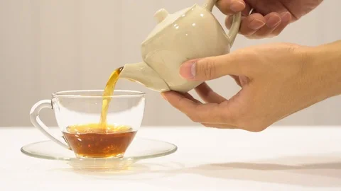 Pouring tea from ceramic teapot two hands Stock Footage 109560495