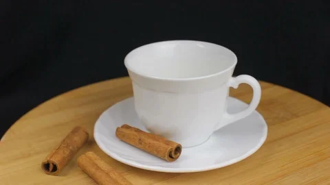 Pouring Tea with Cinnamon on Black Background on Wooden Plate Stock Footage 86857040