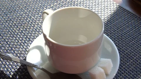 Pouring tea into cup in slow motion close up. Cafe interior. Sunlit table Stock-Footage 80789628