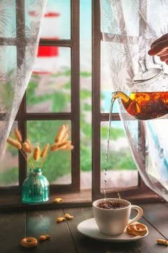 Pouring tea into cup by the window with lighthouse view Stock Photos