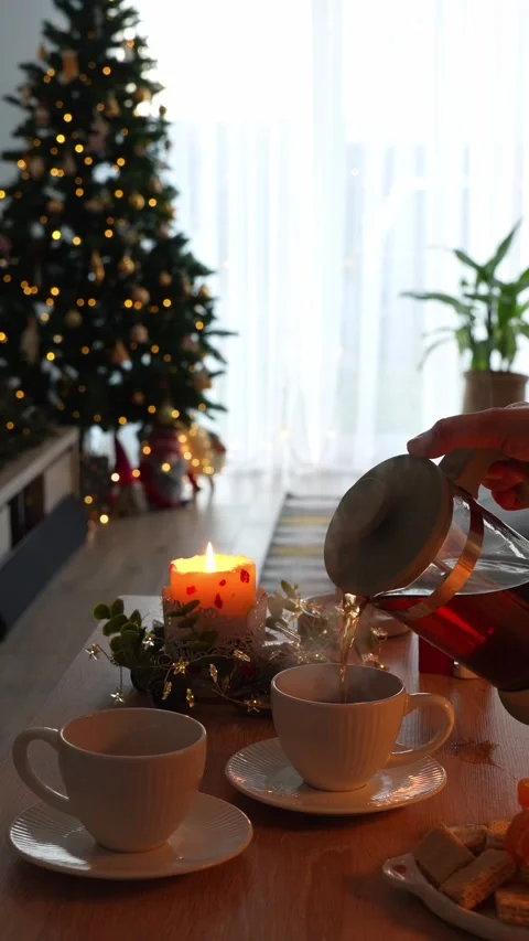 Pouring tea into cups by candlelight and decorated Christmas tree Stock Footage 297774507