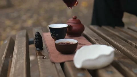 Pouring tea from a glass cup into tea bowls. outdoors tea ceremony Stock Footage 229860834