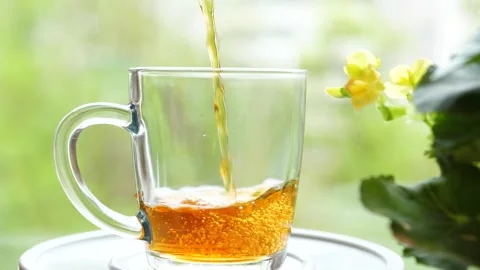 Pouring the tea with leaves of currant, lemon balm, mint, raspberry in a glass Stock Footage 130868258