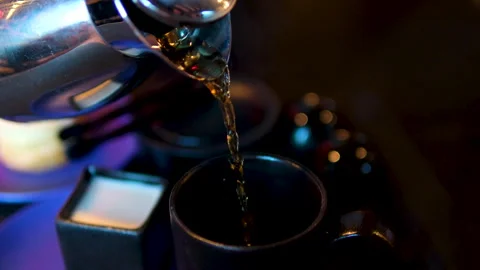 Pouring tea with milk In a dark restaurant black mugs three videos the process Stock Footage 292232698