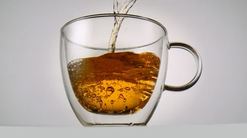 Pouring tea into a tea glass in front of white background in slowmotion Video stock 99701084