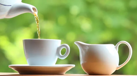 Pouring tea from tea pot into a tea cup Stock Footage