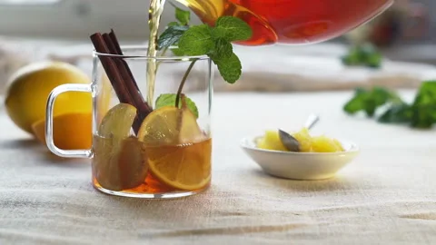 Pouring tea from a teapot into a cup with lemon, cinnamon and mint Stock Footage 122287454