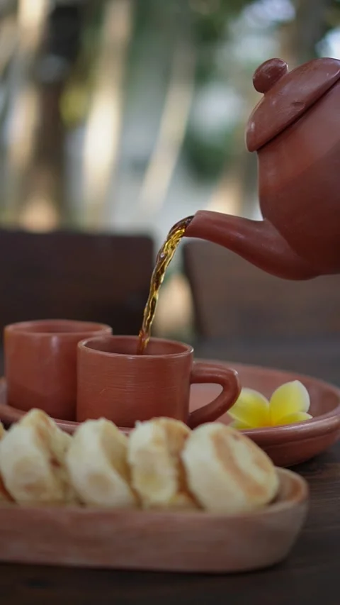 Pouring tea using a Javanese ceramic teapot and cups Stock Footage 283543940