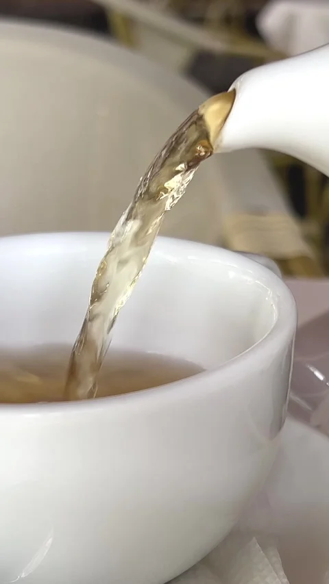 Pouring tea into a white cup cup full of tea with milk being poured in Relaxing Stock-Footage 274482543