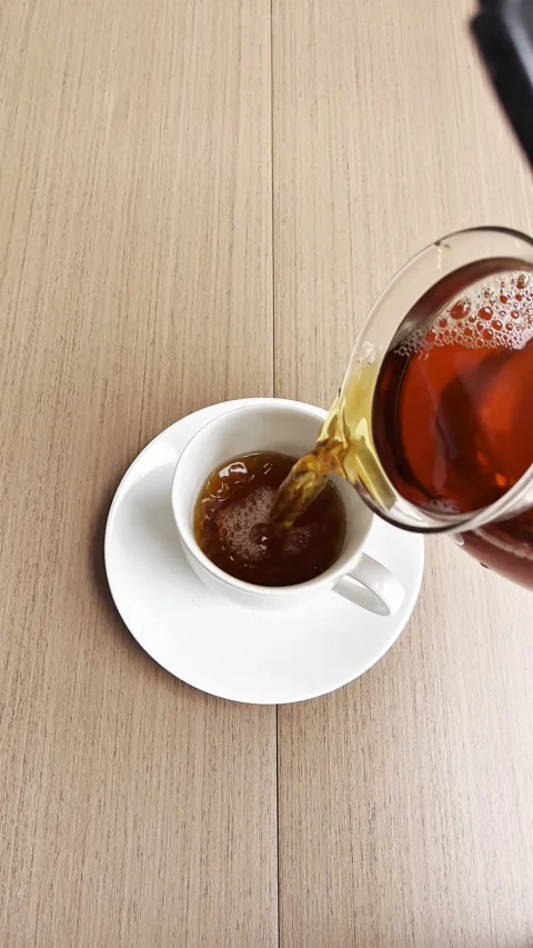 Pouring tea into a white cup, viewed from above Stock Footage 338343346