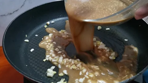 Pouring Thin Brown Sauce in a Frying Pan Stock Footage 234882637