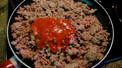Pouring tomato sauce on ground beef on stove Stock Footage 92922196