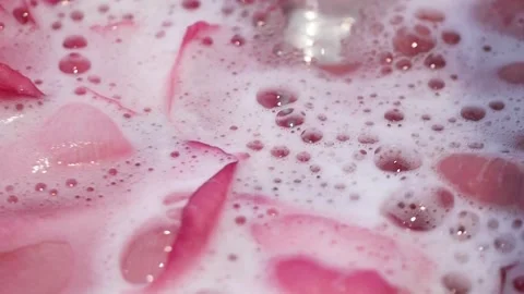 Pouring a tub for relaxing spa bath with rose flower petals, slow motion Video stock 148571253