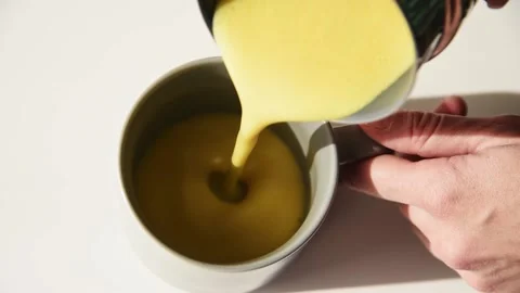 Pouring turmeric latte into the cup. Stock Footage 142825822