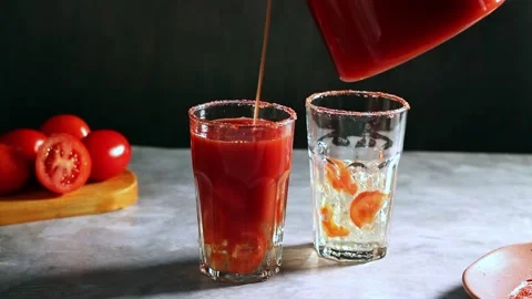 Pouring two glasses with fresh tomato juice. Garnishing glass with tomato slice Stock Footage 300027892