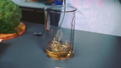 Pouring vegetable oil into plastic container in kitchen setting Vidéo 342827488