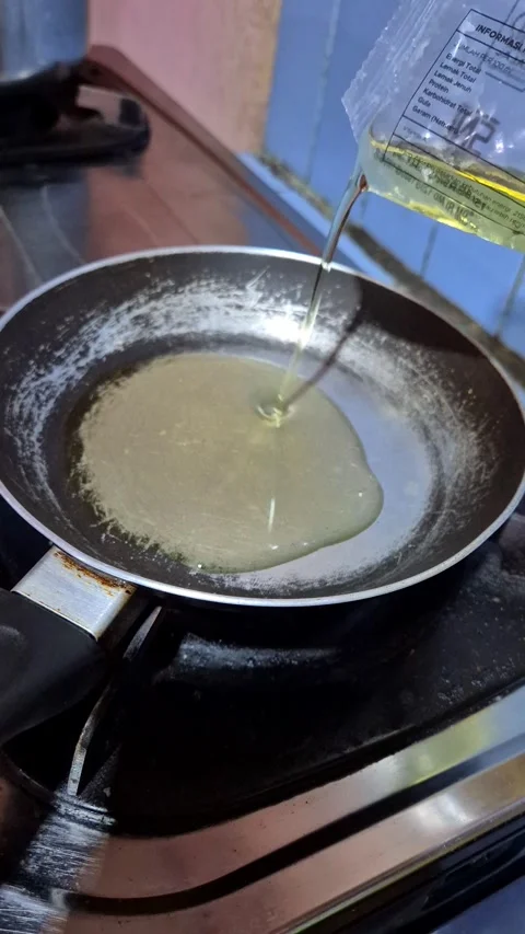 Pouring vegetable oil from a refill pouch into a non-stick pan Stock Footage 337512684