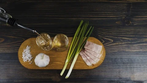 Pouring vodka from a bottle into two small faceted glasses on a wooden board Stock Footage 120181725