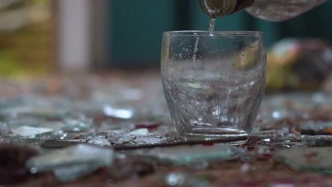 Pouring vodka into a glass on the awesome background of broken glass Видео 80807026