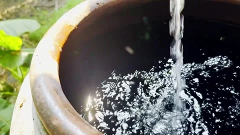 Pouring water in to big earthen jar keep to use Stock Footage 302707252