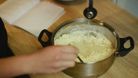 Pouring water into flour mixture for making dough Stock Footage 340078050