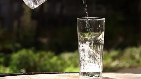 Pouring water into glass placed on table Stock Footage 73776273