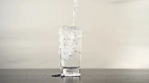 Pouring water into a glass until it overflows Stock Footage