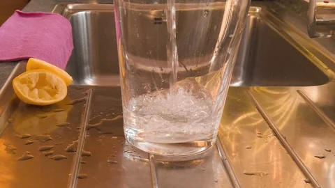 Pouring water into an huge empty glass - slow motion Stock Footage 104973682