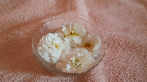 Pouring Water Over Floating White Flowers in Glass Bowl Stock Footage 333562146